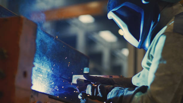 istock Worker in protective workwear welding metal part with sparks 1858052455