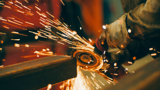 istock Worker using angle grinder in factory. Bright sparks and flashes 1858052459