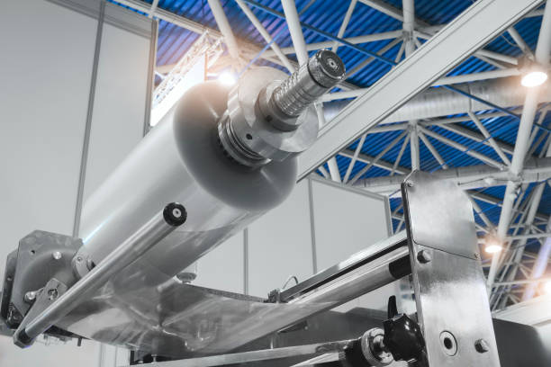istock Automatic polyethylene plastic bag production machine with lighting effect. Close-up of the roller of the plastic bag production machine in the light blue scene. product packaging concept 1858064088