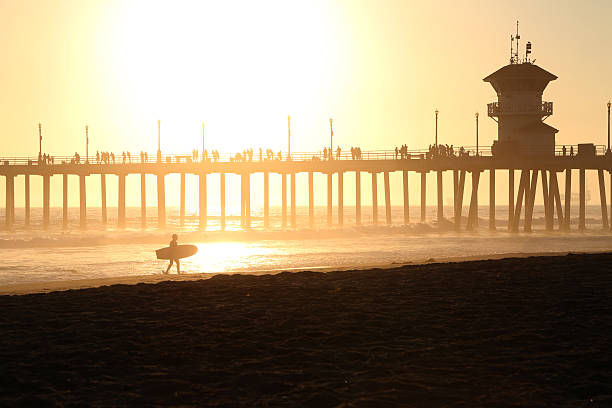 Sunset at Huntington Beach pier in California Sunset at Huntington Beach pier in California with a silhouette of a surfer. huntington beach california stock pictures, royalty-free photos & images