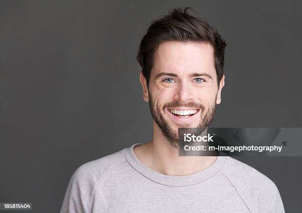 Retrato De Un Hombre Joven Feliz Sonriendo Sobre Fondo Gris Foto de stock y más banco de imágenes de Hombres