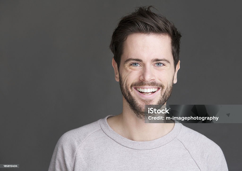 Retrato de um homem jovem feliz sorrindo em Fundo cinza - Foto de stock de Homens royalty-free