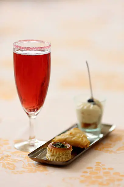 Details of a glass of kir royal and amuse bouche.