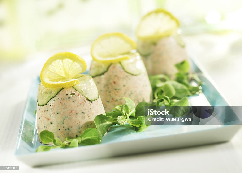 three towers of salmon mousse three towers of salmon mousse served on a light blue plate with a garnish lemon and field lettuce Salmon - Seafood Stock Photo