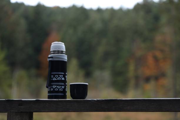 pouring tea  from thermos near by a lake