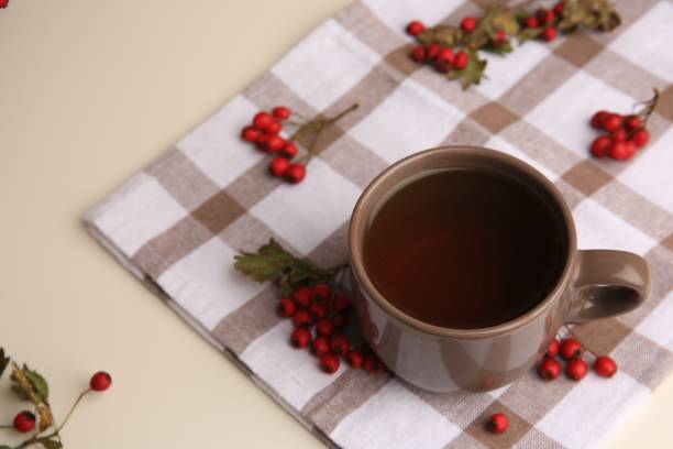 istock Brown cup with hawthorn tea and berries on beige table 1858200951