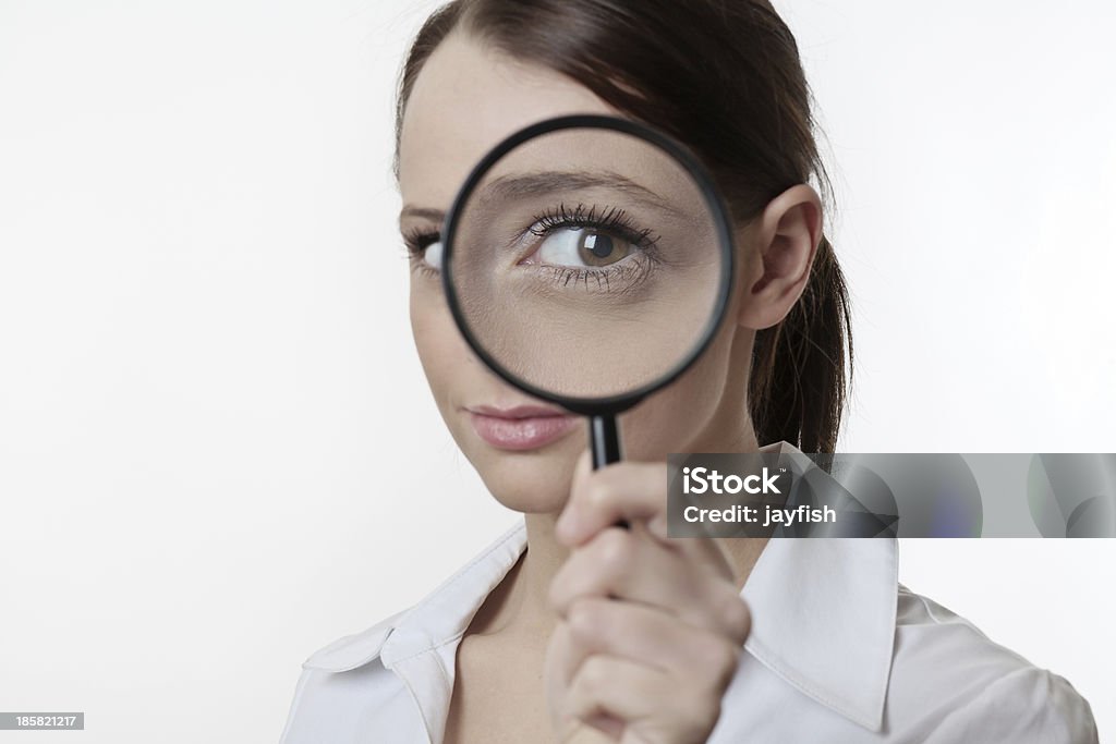 get a better look Confident young woman looking through a magnifying glass Adult Stock Photo