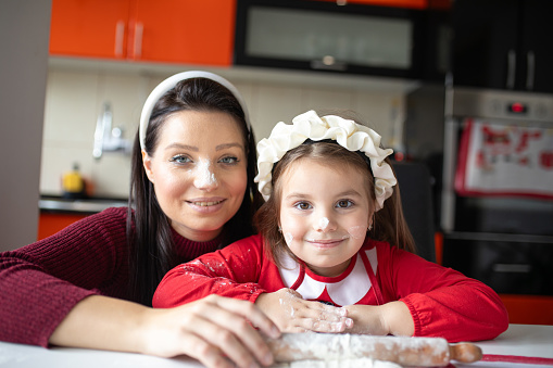 Flour on faces of mother and daughter while making cookies