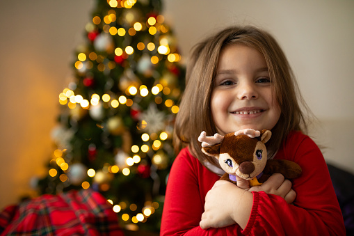 Cute little girl find reindeer toy under the tree