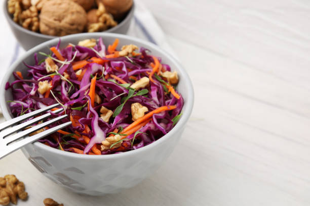 istock Tasty salad with red cabbage and walnuts on white wooden table, closeup. Space for text 1858259826