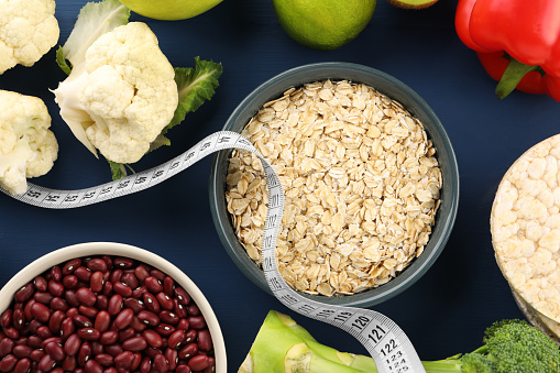 Healthy diet. Different products and measuring tape on blue wooden table, flat lay