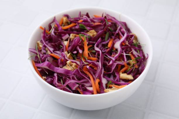 istock Tasty salad with red cabbage and walnuts in bowl on white tiled table, closeup 1858261521