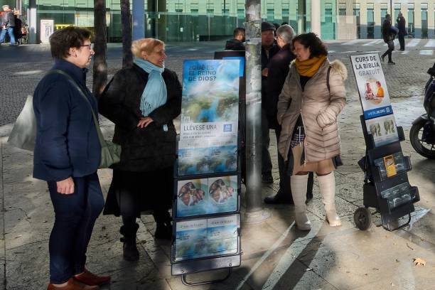 groupe de personnes discutant dans une rue urbaine à côté d’une publicité religieuse. - bible stand photos et images de collection