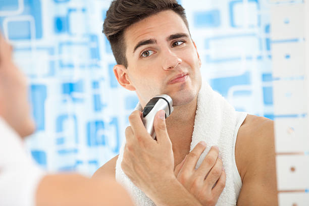 riflessione di giovane uomo in specchio - shaving men electric razor reflection foto e immagini stock