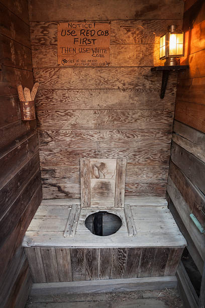 Outhouse Interior Old time wooden outhouse with electric lamp, South Dakota Outhouse stock pictures, royalty-free photos & images