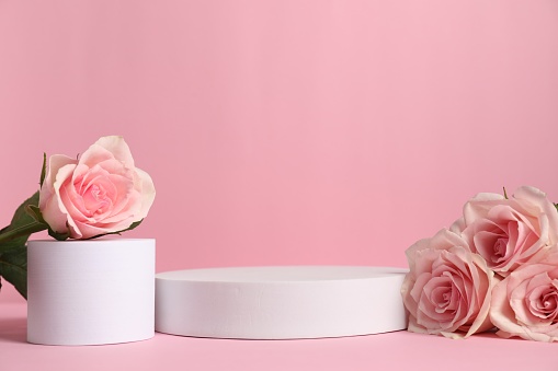 Stylish presentation of product. Beautiful roses and geometric figures on pink table, space for text