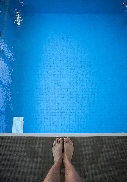 man looking down on feet on diving platform