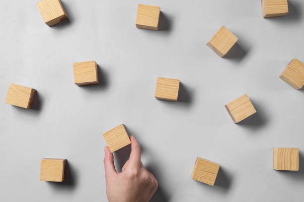 istock Woman arranging wooden cubes at light grey table, top view 1858337986