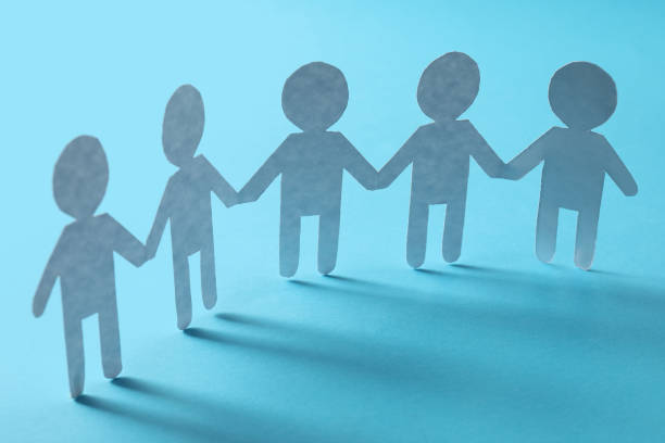 istock Teamwork concept. Paper figures of people holding hands on light blue background 1858338491