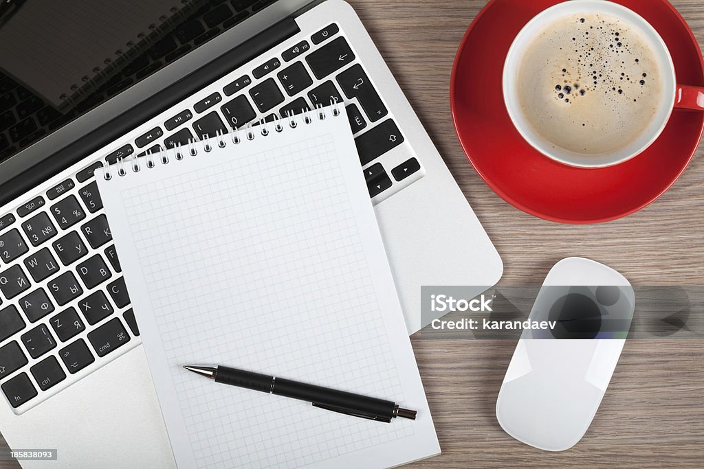 Blank notepad over laptop and coffee cup Blank notepad over laptop and coffee cup on office wooden table Above Stock Photo