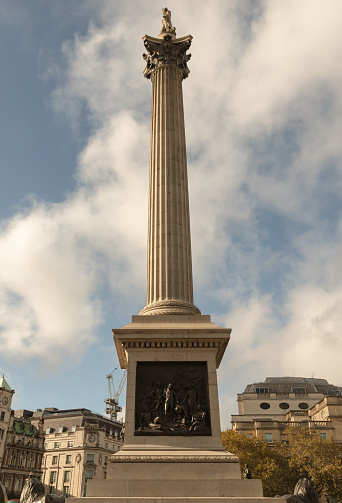 Charles I Monument (cast in 1633 by Hubert Le Sueur and erected in this position in 1675) and Nelson's Column (built by 1843 to a design by William Railton).. People can be seen in the distance.