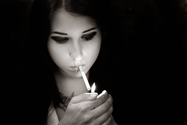 istock Girl lights a cigarette in black & white 185840472