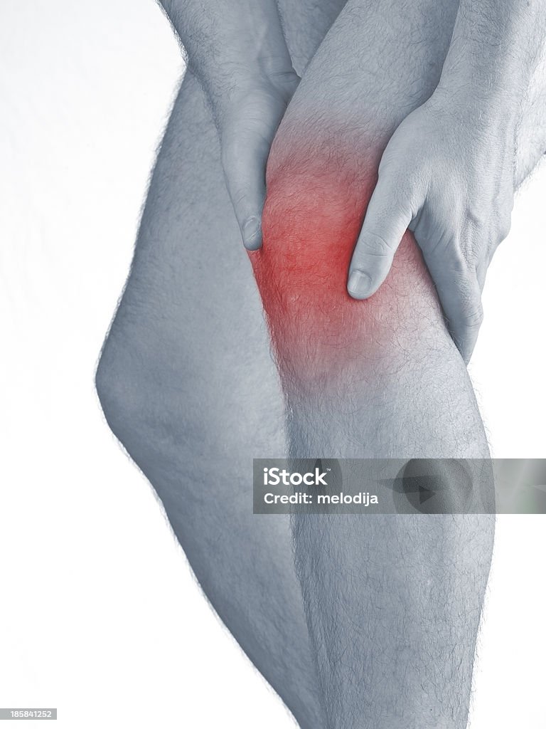 Acute pain in a man  knee. Acute pain in a man  knee. Male holding hand to spot of knee-aches. Concept photo with Color Enhanced blue skin with read spot indicating location of the pain. Isolation on a white background. Pain Stock Photo