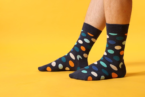 Man in stylish colorful socks on yellow background, closeup. Space for text