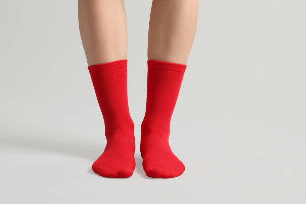 Woman in stylish red socks on light grey background, closeup