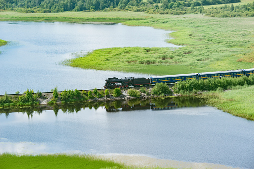 Retro steam train moves along the lake.