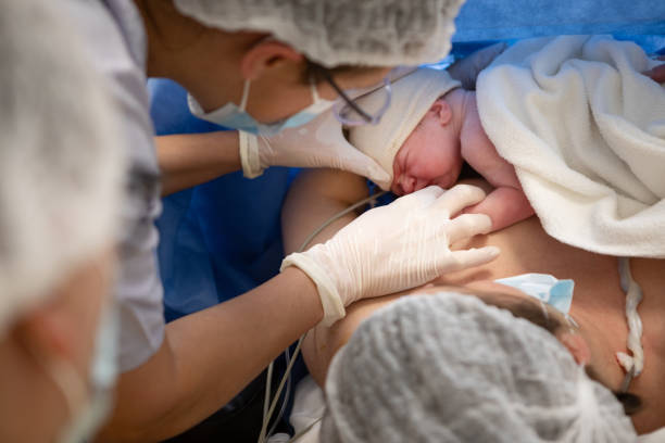 Mother breastfeeds her newborn baby after a cesarean section stock photo