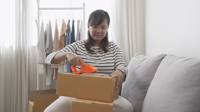 Woman packing a box using a duct tape prepare to deliver