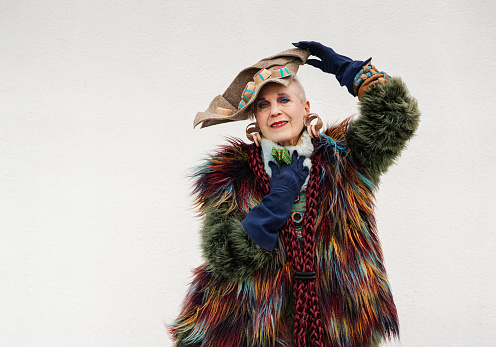 Happy senior woman wearing colorful fur posing over white background, New York City