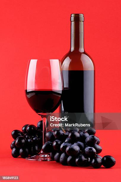 Vinho Sobre Fundo Vermelho - Fotografias de stock e mais imagens de Fundo Colorido - Fundo Colorido, Garrafa de Vinho, Uva