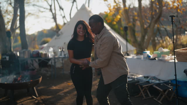 Multi-ethnic couple dancing together during camping in camping site in nature