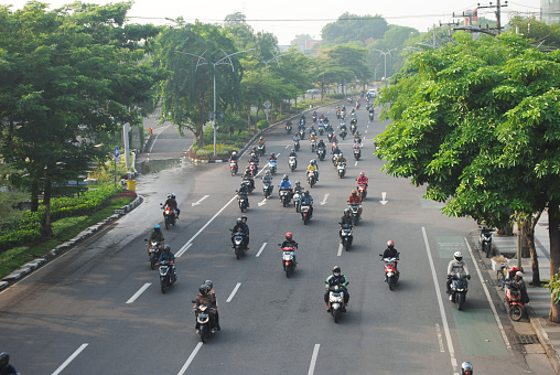 Surabaya, Indonesia, 12-13-2023:\nMotorcyclist going to work in Monday morning at Ahmad Yani street, Surabaya, Indonesia.