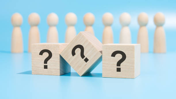istock three wooden cubes with question marks are placed on a blue table amid wooden figurines, representing business and education. the close-up focuses on the cubes 1858538488
