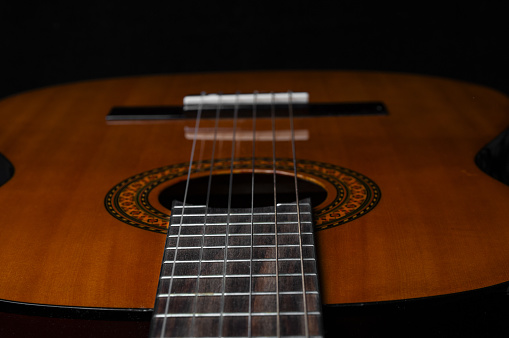 Acoustic  guitar close up  on a black background. Front focus