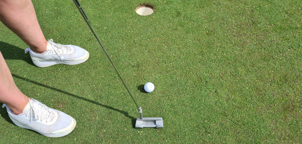 istock Closeup of lady golfer puttering ball into hole 1858669949