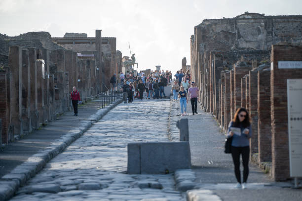 People walking through the Ancient Pompeii (UNESCO World Heritage Site). Paving stones of Via del Foro in November 2023. Pompeii, Italy : 2023 November 16 : People walking through the Ancient Pompeii (UNESCO World Heritage Site). Paving stones of Via del Foro in November 2023. victims the ruins of pompeii stock pictures, royalty-free photos & images
