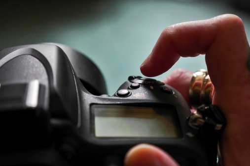 Finger clicking on shutter-release of a dslr camera, close shot with shallow depth of field nod emphasis on finger clicking.