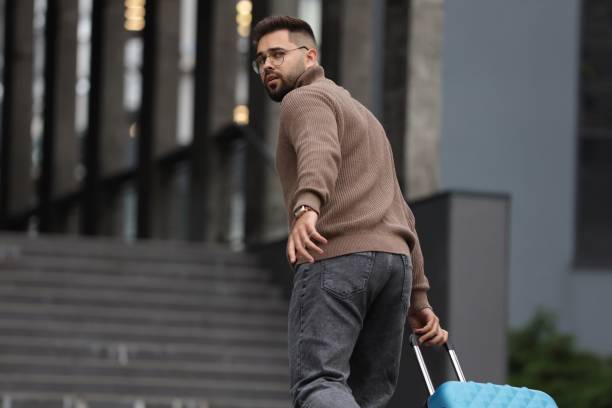 istock Being late. Worried man with suitcase running towards building outdoors, space for text 1858753342