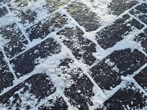 Close-up of brown street tiles covered with white snow. Winter background