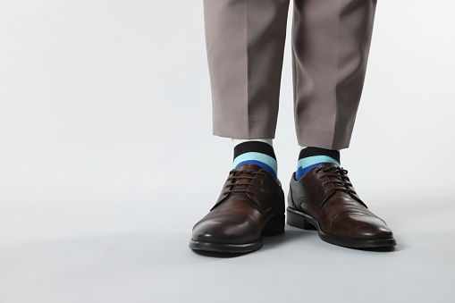 Man in stylish colorful socks, shoes and pants on white background, closeup. Space for text