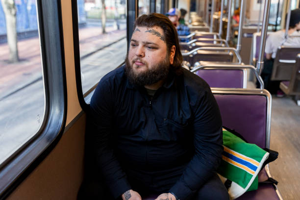 istock Tattooed Man Rides Public Transit Train Through City for Work 1858811769