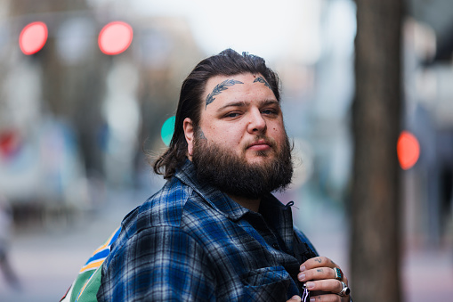 Portraits of a man in his 30s in downtown Portland Oregon. He is sporting some cool face and hand tattoos. Shot with a variety of backgrounds and copy space provided.