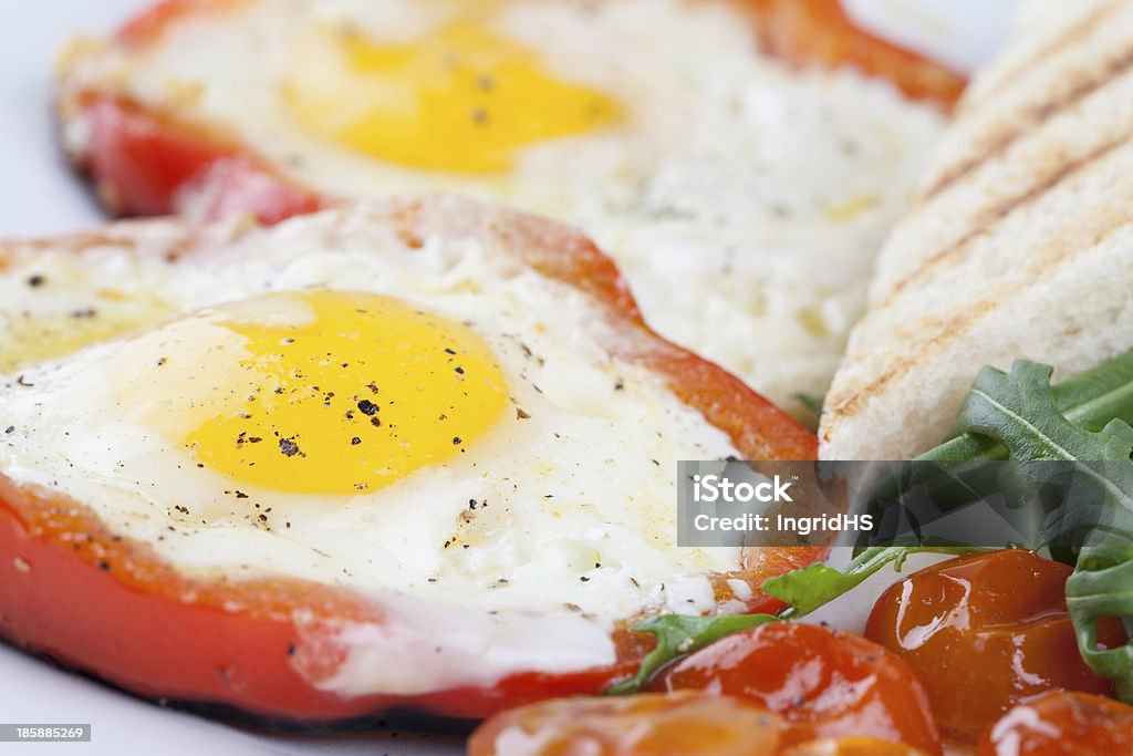 Fried eggs Eggs fired in bell pepper frames with cherry tomatoes and arugula.  American Culture Stock Photo
