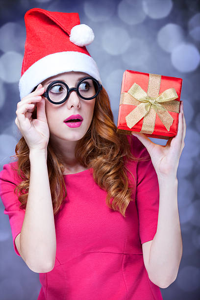 istock Redhead girl in christmas hat with gift. 185885301