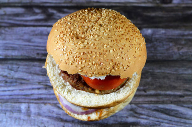 spicy fried beef burger cooked in a boiling shallow oil with slices of  tomatoes, onions, bell peppers in burger bun topped with sesame seeds, Fast food, Junk food concept, beef meat burger sandwich