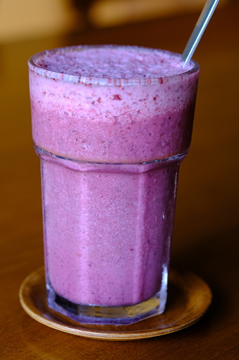 lassi mulberry drink in a clear glass. Lassi is a cold yoghurt drink mix with fruit juice.
